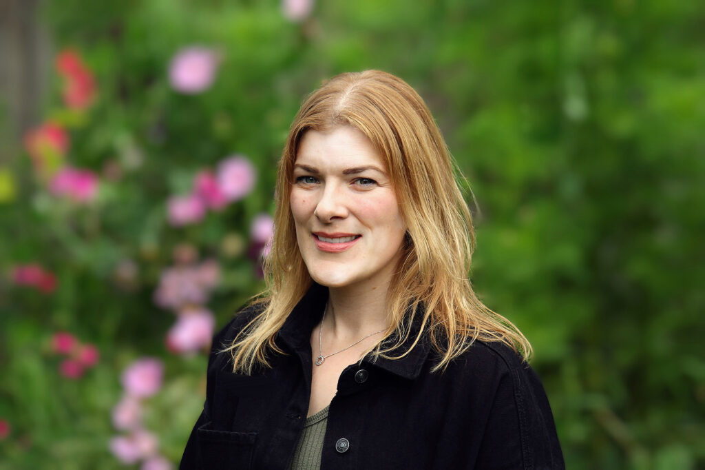 A woman in front of flowers.