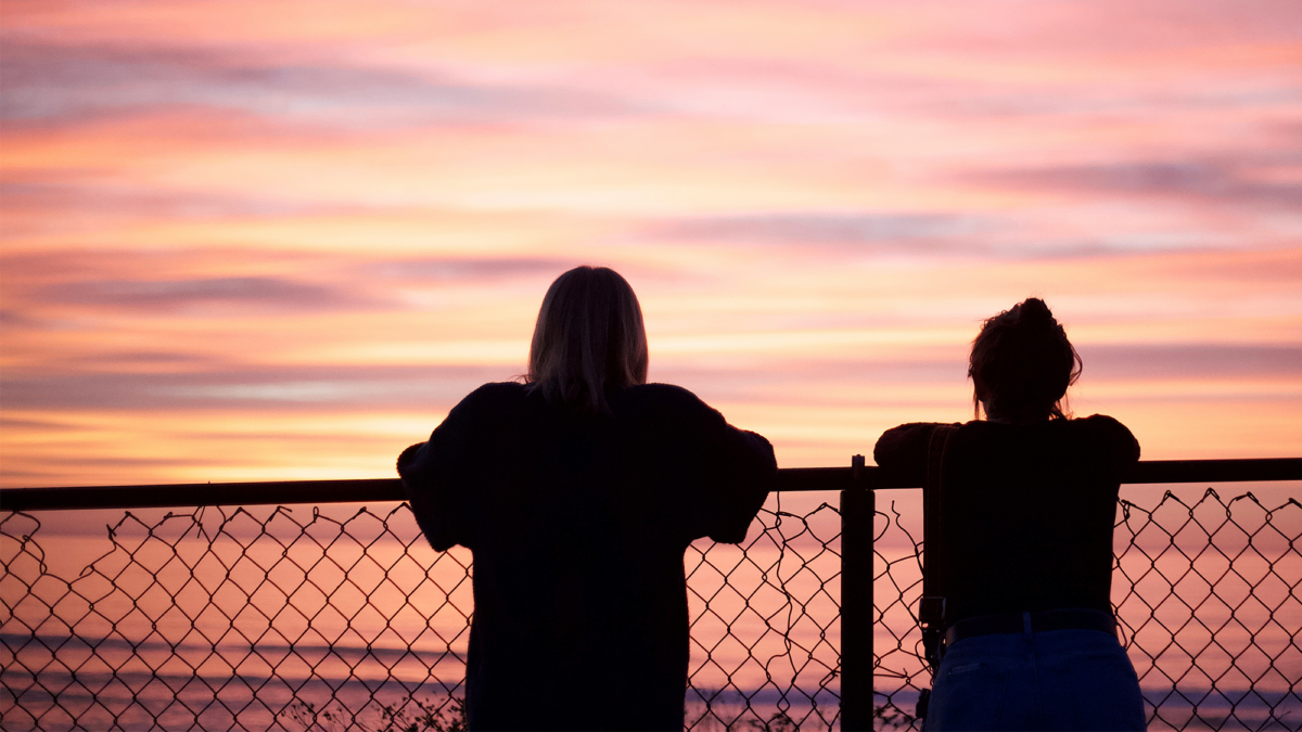 Silhouette of two women looking out at a sunset