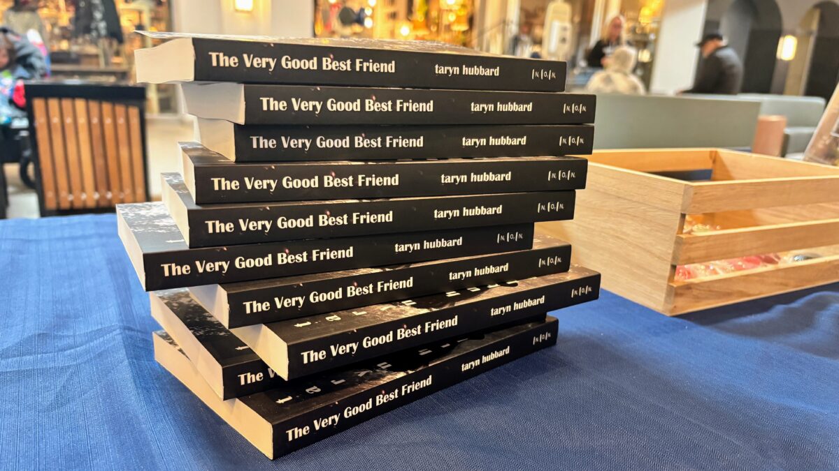A stack of books with a black spine that has letters in white that read The Very Good Best Friend by Taryn HUbbard